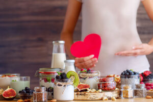 Una mesa con diferentes productos lácteos, y detrás de ella hay una persona desosteniendo un corazón.